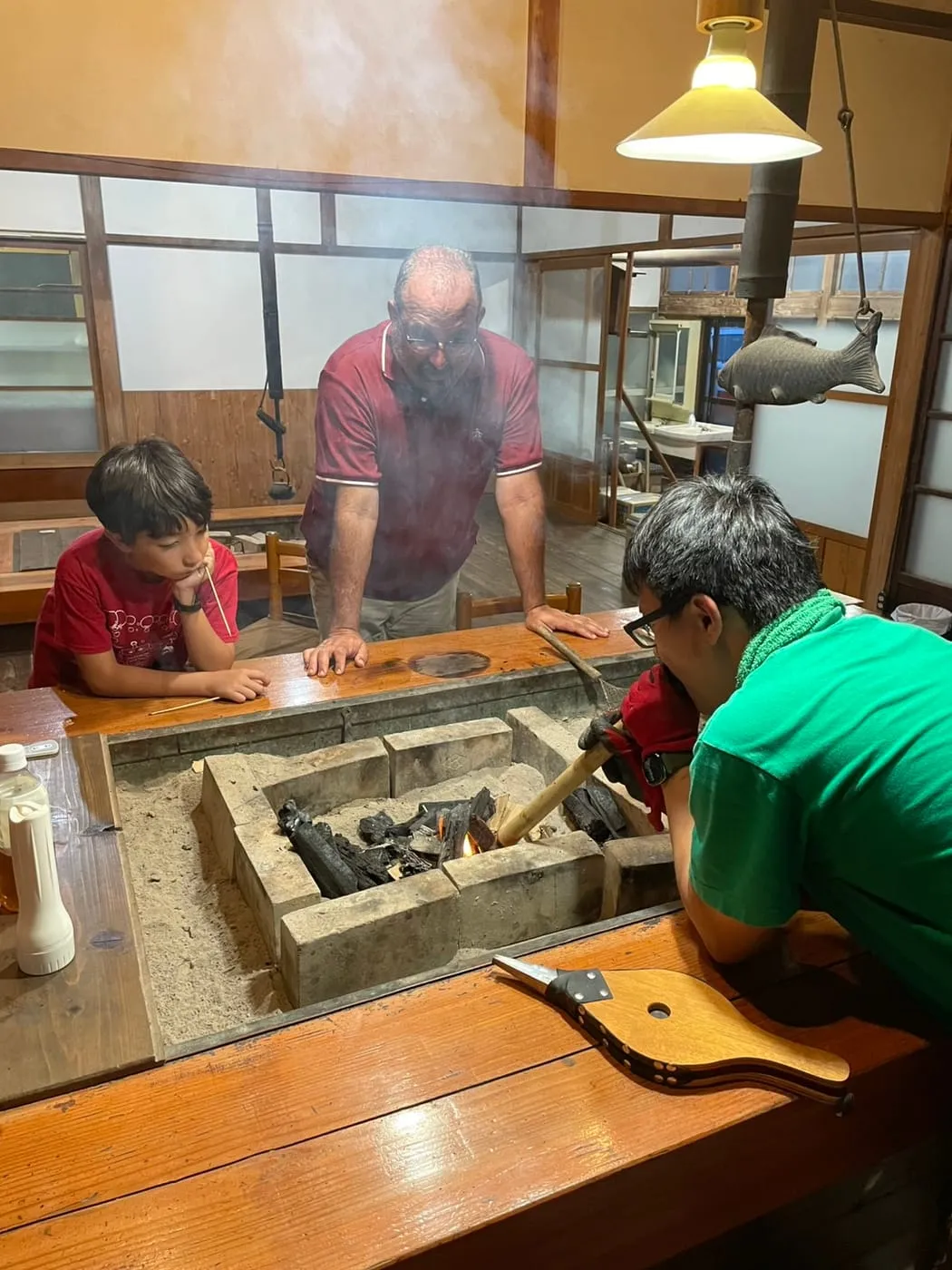 Using a bamboo blowpipe to keep the charcoal in the irori going