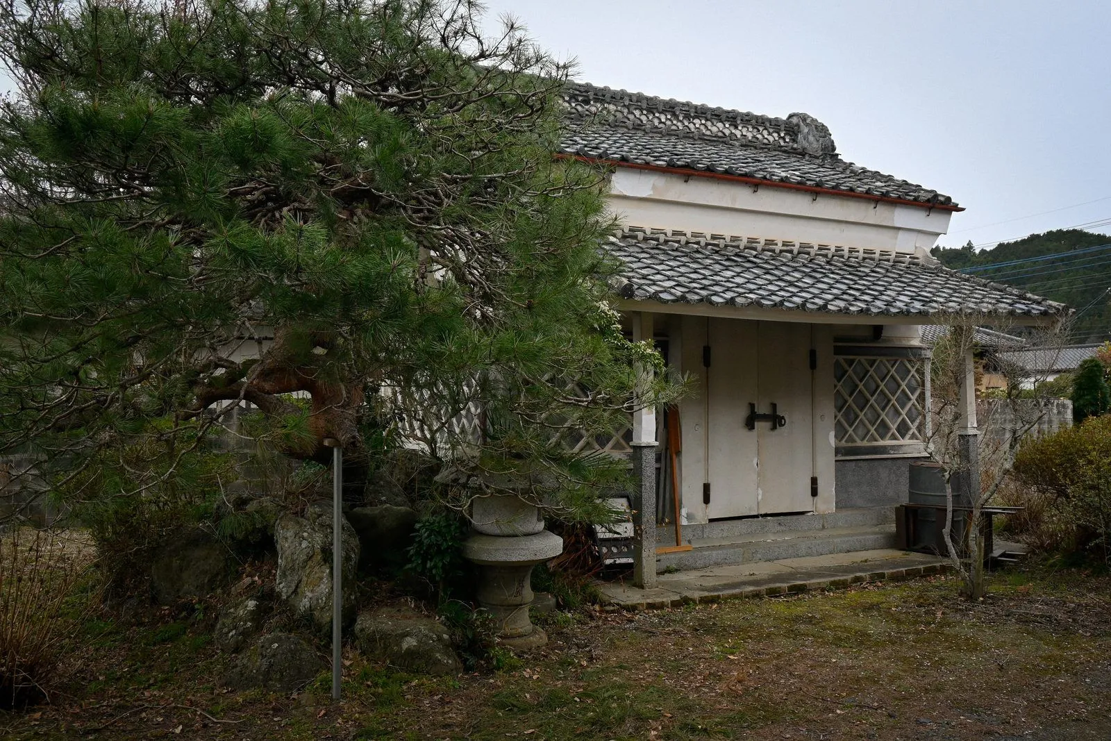 松と石灯籠の奥に建つ、白壁の蔵